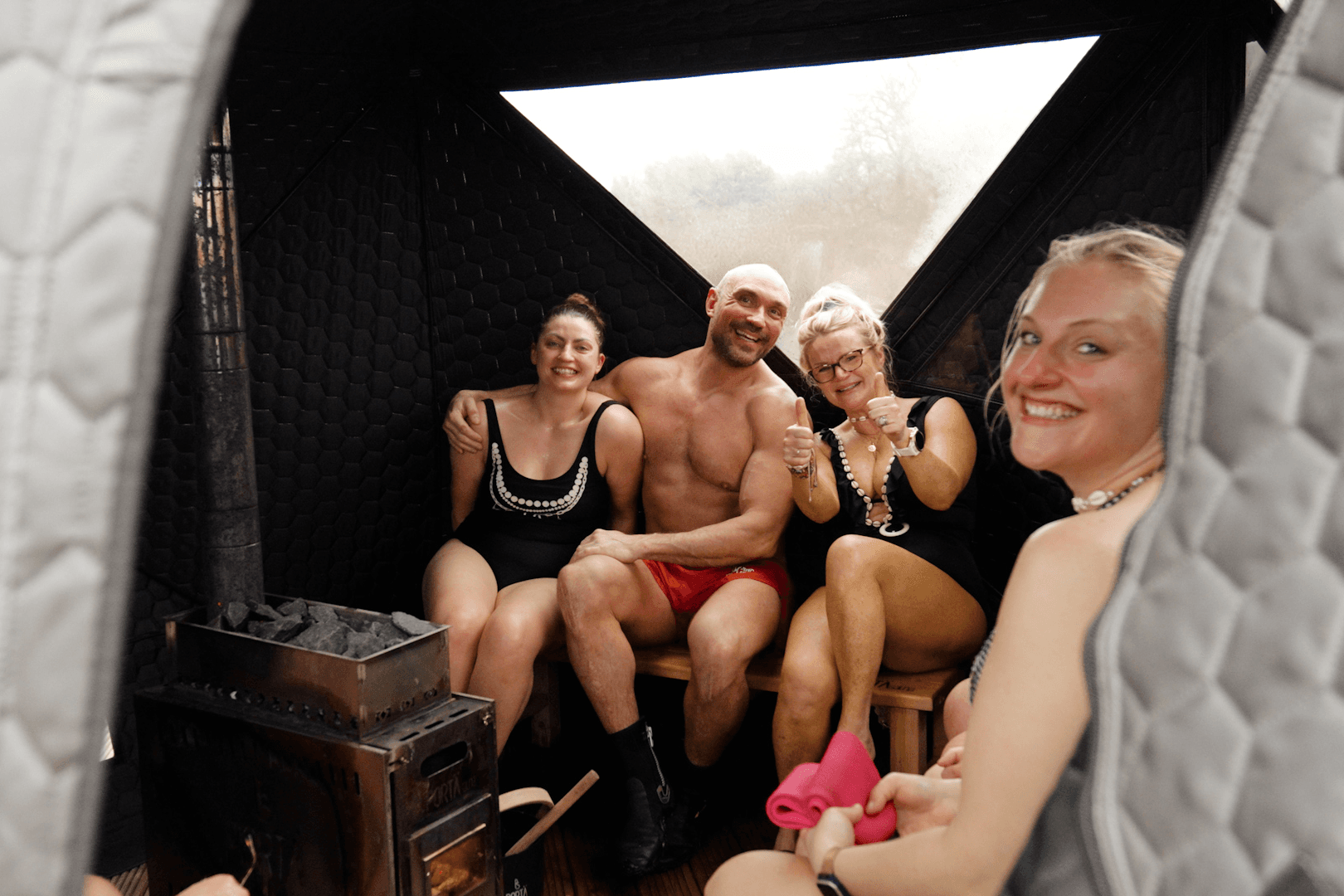 Group of friends laughing together inside the sauna tent